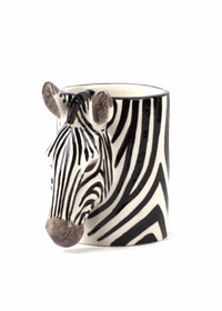 A ceramic pencit pot shaped like a zebra head, featuring a black and white striped pattern with a realistic zebra nose and ears, set against a plain white background.