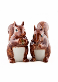 Two ceramic squirrel figurines in reddish-brown and white glaze, standing side by side against a plain white background.