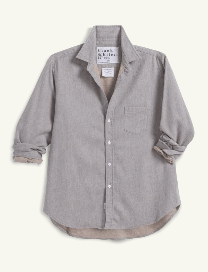 A light gray long-sleeve button-up shirt by Frank & Raven, featuring a chest pocket, rolled cuffs, and a visible inner lining in a warm taupe-beige color, laid flat against a light cream background.