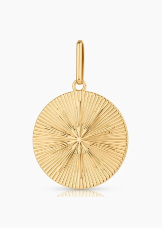 A gold round pendant charm with a textured sunburst or radial line pattern, featuring a polished bail at the top, shown on a clean white background with a subtle reflection below.