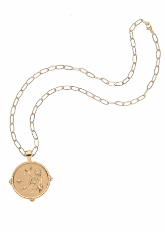 A gold pendant necklace featuring a circular medallion with an astrological or celestial figure, displayed on a clean white background.