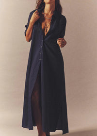 Woman wearing a long navy blue shirt dress against a beige background